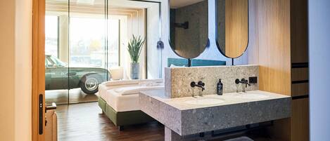 Un baño moderno con un espejo grande, lavamanos dobles y un estante integrado.