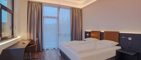 Una habitación de hotel moderna con una cama grande, un escritorio y una silla.