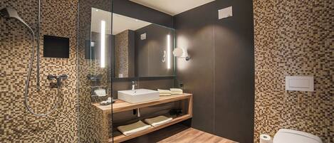 Un baño moderno con cabina de ducha de vidrio, tocador de madera y un espejo grande.