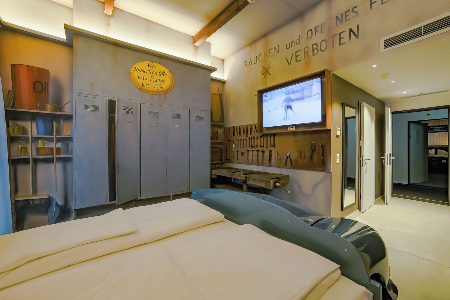 A room with a bed, a television, and a wall-mounted tool rack.