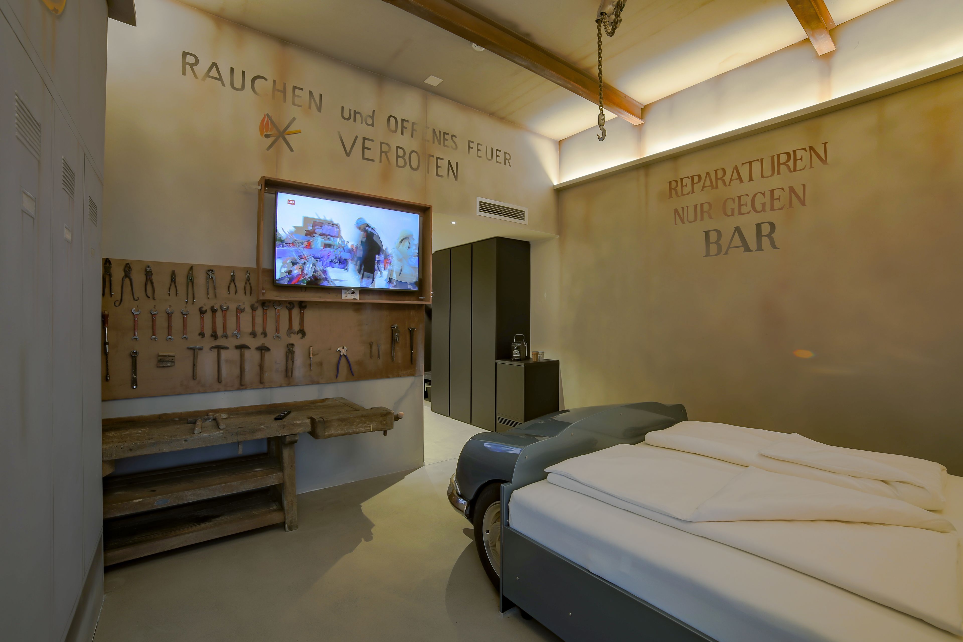 A modern hotel room with a bed, a TV mounted on the wall, and a wooden bench.
