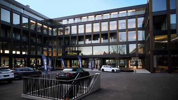 A modern hotel with a glass facade, a restaurant, and a parking area with cars. - Hotel von Rotz (Wil)