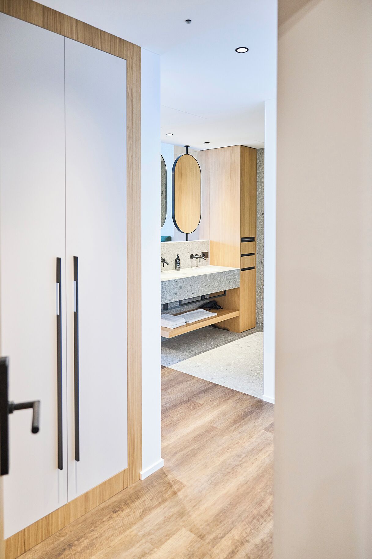 A modern bathroom with a wooden vanity, a mirror, and a sink.