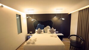Una habitación de hotel moderna con una cama grande, mesitas de noche, un escritorio y una silla.