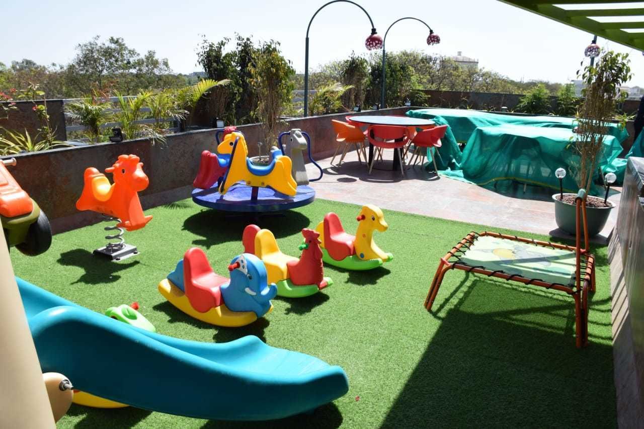 A rooftop playground with various play equipment including a slide, swings, and a merry-go-round.