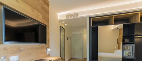 Una habitación de hotel moderna con un escritorio de madera, un espejo grande, una cama y un vestidor.
