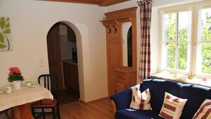 A cozy living room with a blue sofa, wooden table, and a dining table with chairs. - Wachinger Hof (Bad Feilnbach)