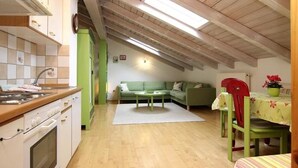 A compact kitchen with a dining area, a green sofa, and a red chair. - Wachinger Hof (Bad Feilnbach)