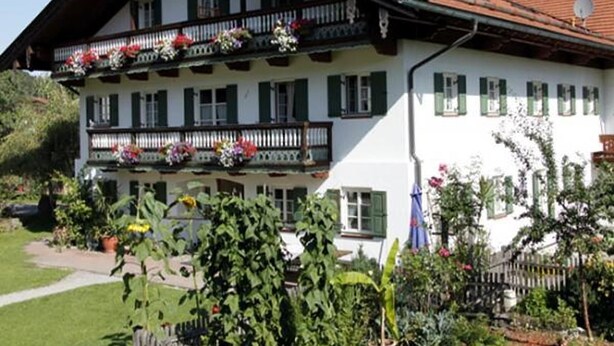 A traditional chalet with a balcony, white walls, and green shutters. - Wachinger Hof (Bad Feilnbach)