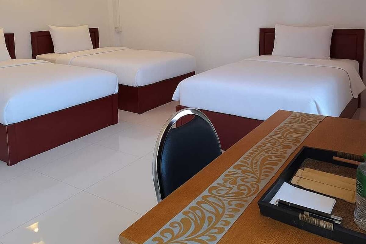 A hotel room with two beds, a desk with a tray of toiletries, and a wall-mounted light fixture.