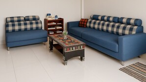 A living room with two sofas, a coffee table, and a bookshelf. - Sipanya Guesthouse (Phonsavan)