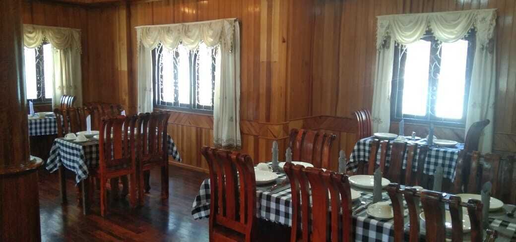 A dining area with wooden walls and tables set with checkered tablecloths and chairs.