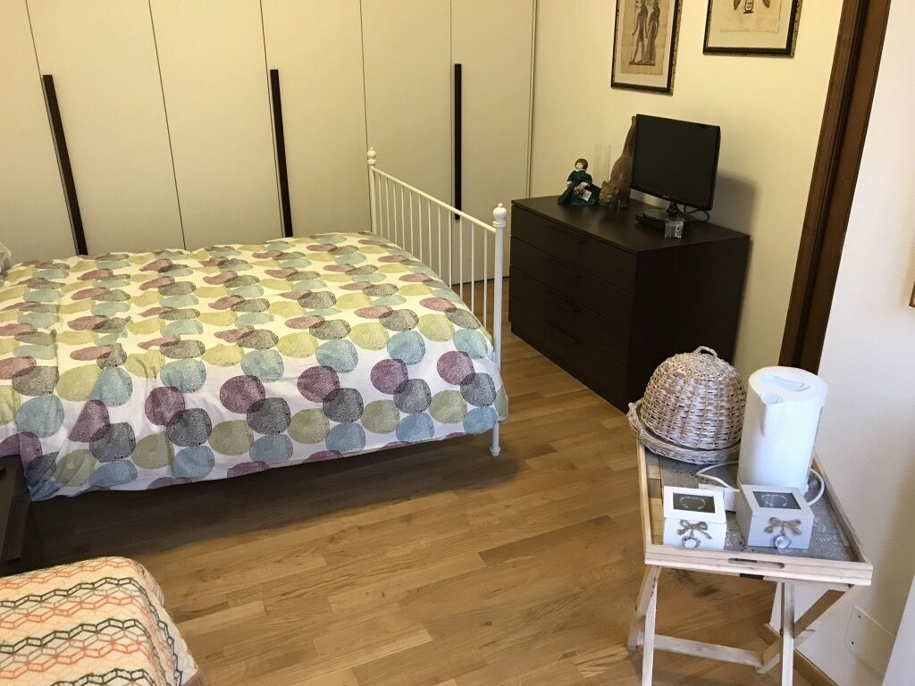 Un dormitorio con cama, tocador, televisor y una mesita con adornos.
