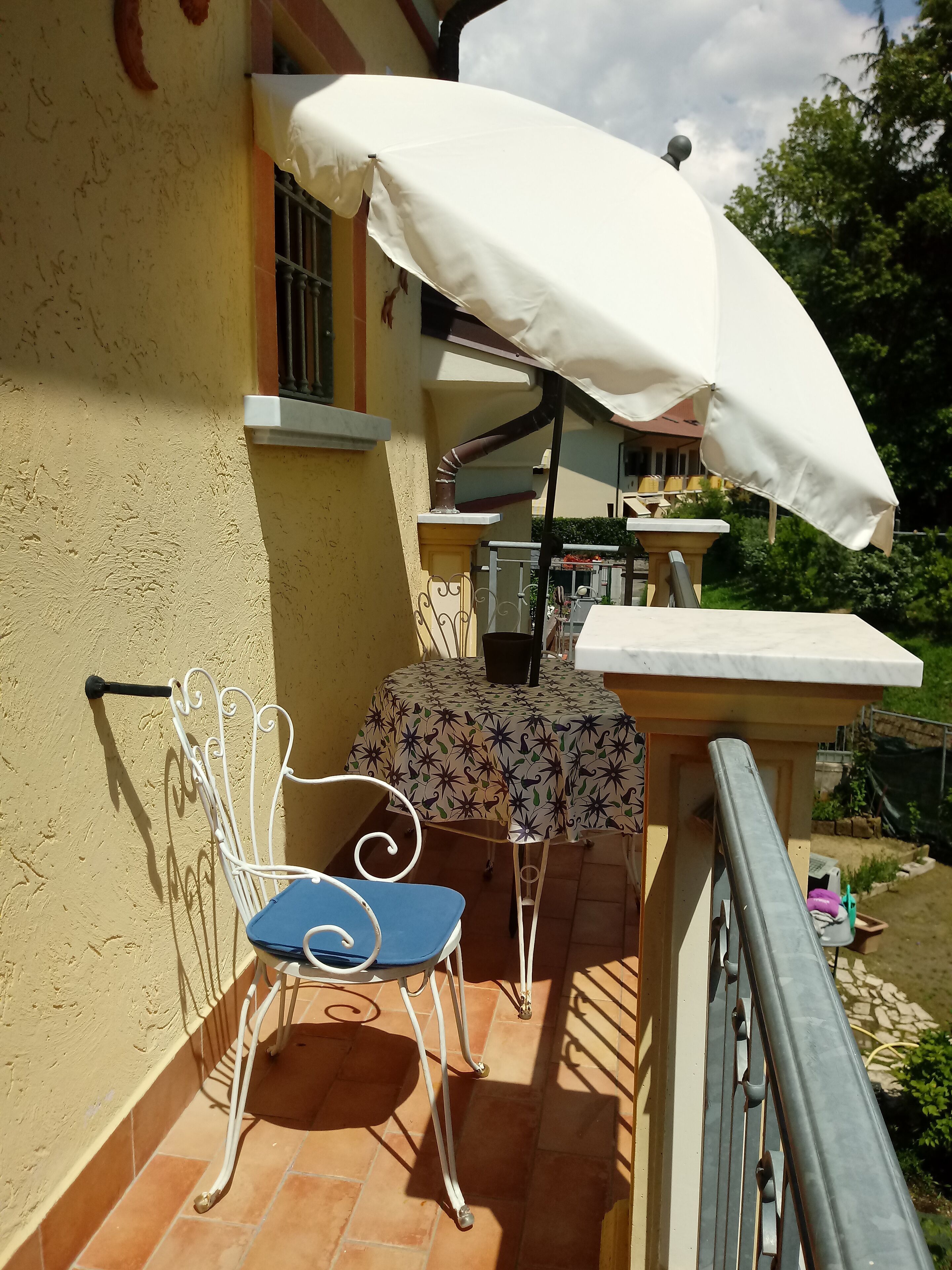 En terrasse med et bord, stole, en parasol og gelænder.