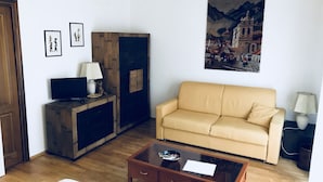 Ein Wohnzimmer mit einer Couch, einem Couchtisch, einem Fernseher und gerahmten Bildern an der Wand.