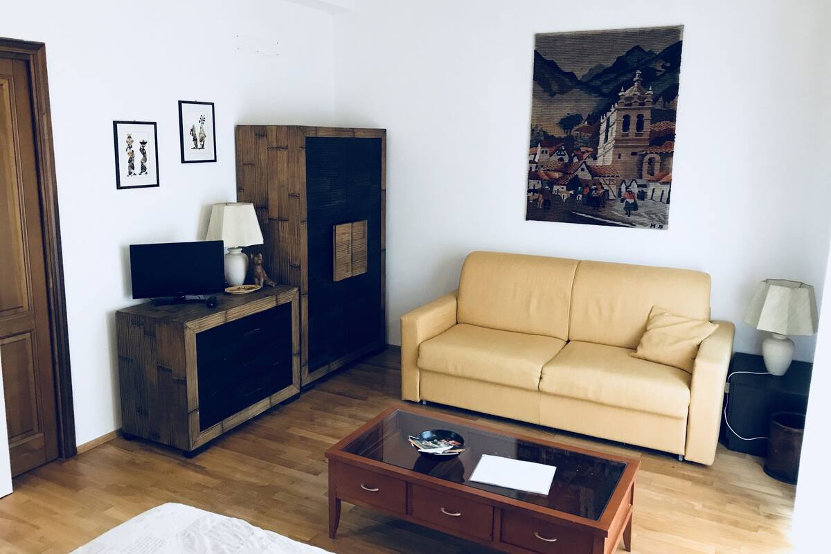 A living room with a sofa, a coffee table, a TV, and framed pictures on the wall.