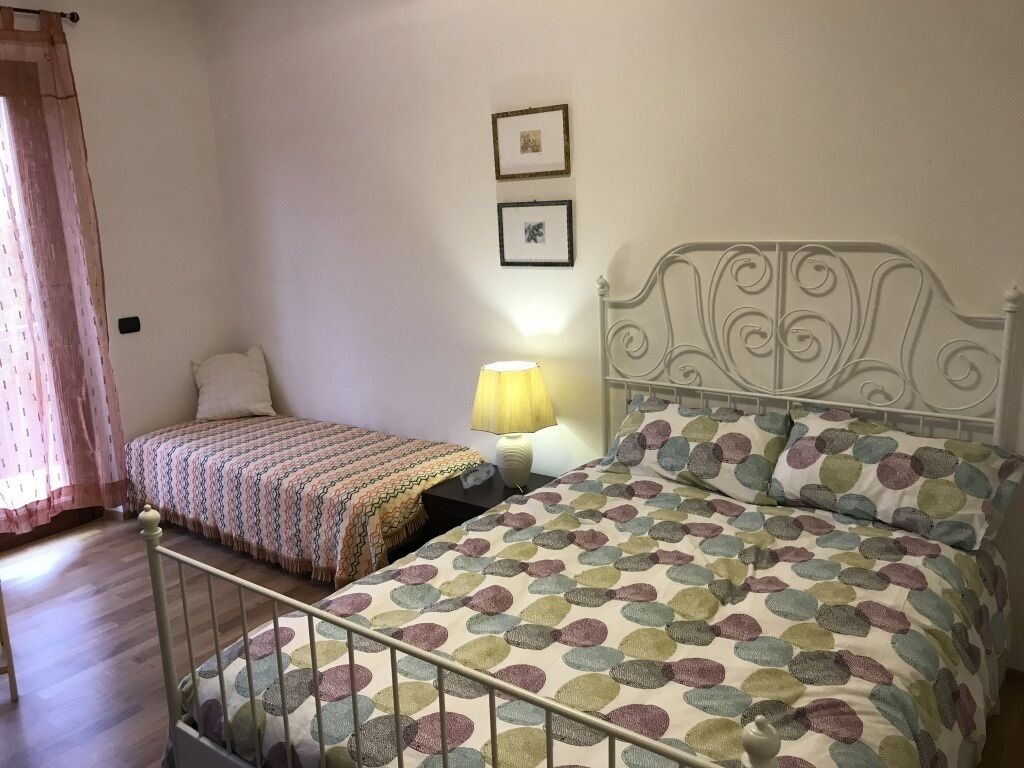 Ein Schlafzimmer mit zwei Betten, einem Nachttisch, einer Lampe und zwei gerahmten Bildern an der Wand.