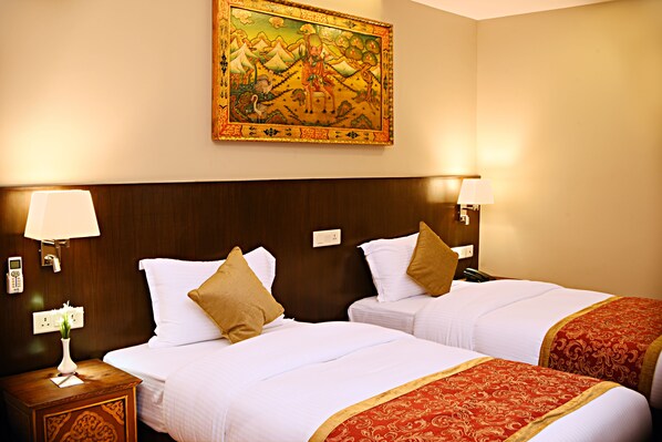 A hotel room with two beds, a wooden headboard, a wall-mounted painting, and bedside lamps.