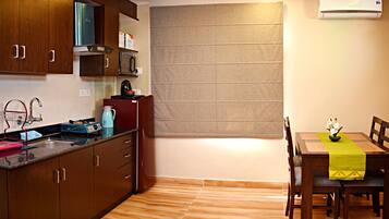 Una cocina compacta con armarios de madera, un microondas integrado y una ventana con persianas.