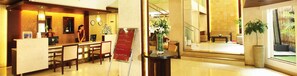 A hotel lobby with a reception desk, seating area, and a staircase leading to an upper floor. - Broad Bean Cochin (Kanayannur)