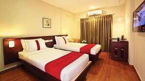 A hotel room with two beds, a TV, a small table, and a curtain. - Broad Bean Cochin (Kanayannur)