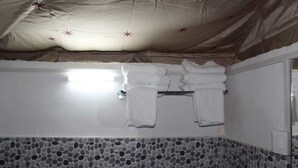 Une salle de bain avec un sol carrelé, un porte-serviettes avec des serviettes pliées et un miroir au mur.