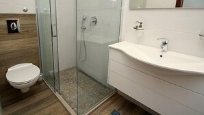 A modern bathroom with a glass-enclosed shower, a white sink, and a toilet. - Villa Belvedere (Makarska)