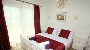 A neatly arranged bedroom with a large bed, a bedside table, and a nightstand. - Villa Belvedere (Makarska)