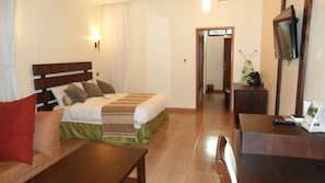 A hotel room with a bed, a desk, a chair, a television, and a mirror.