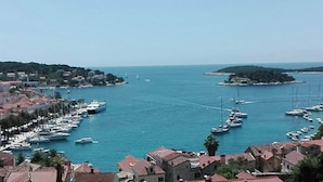 Un pueblo costero con un puerto deportivo lleno de barcos, rodeado de edificios con tejados rojos.