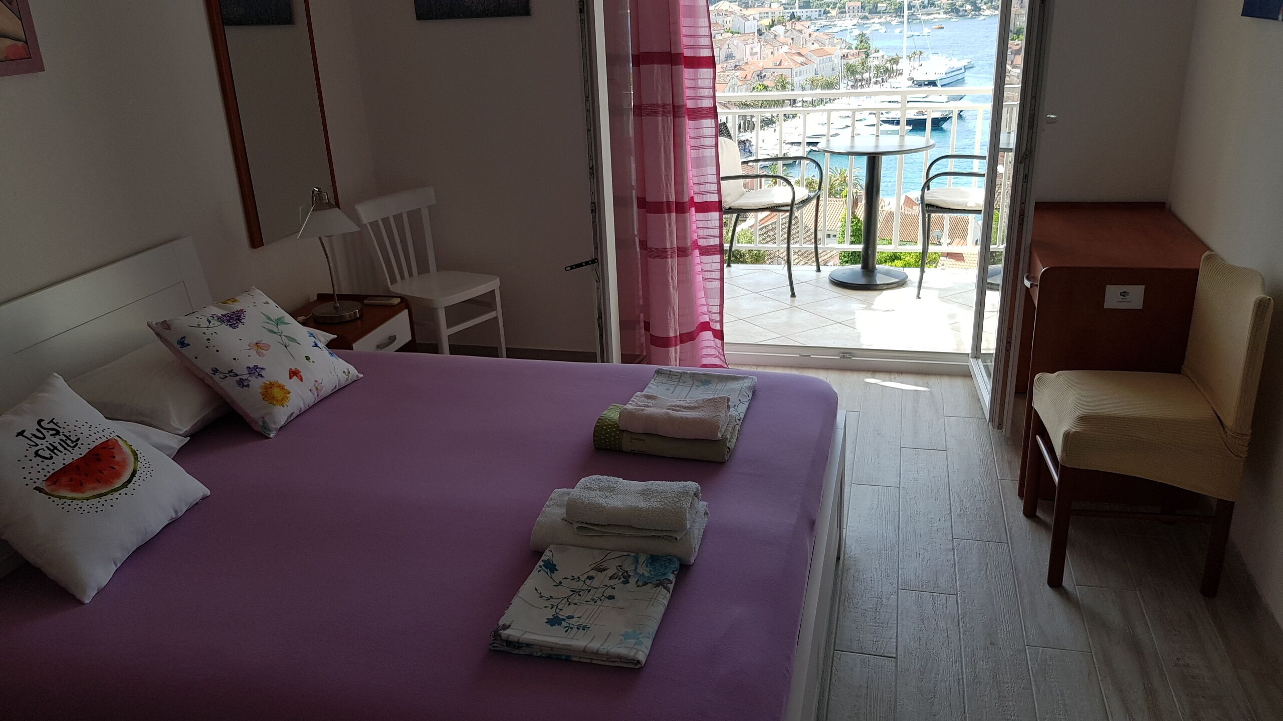 Une chambre d’hôtel avec un lit, une chaise, une table et une vue sur la mer et les bateaux.