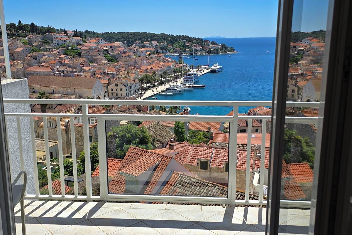 A balcony with a view of a coastal town, including buildings and a marina.