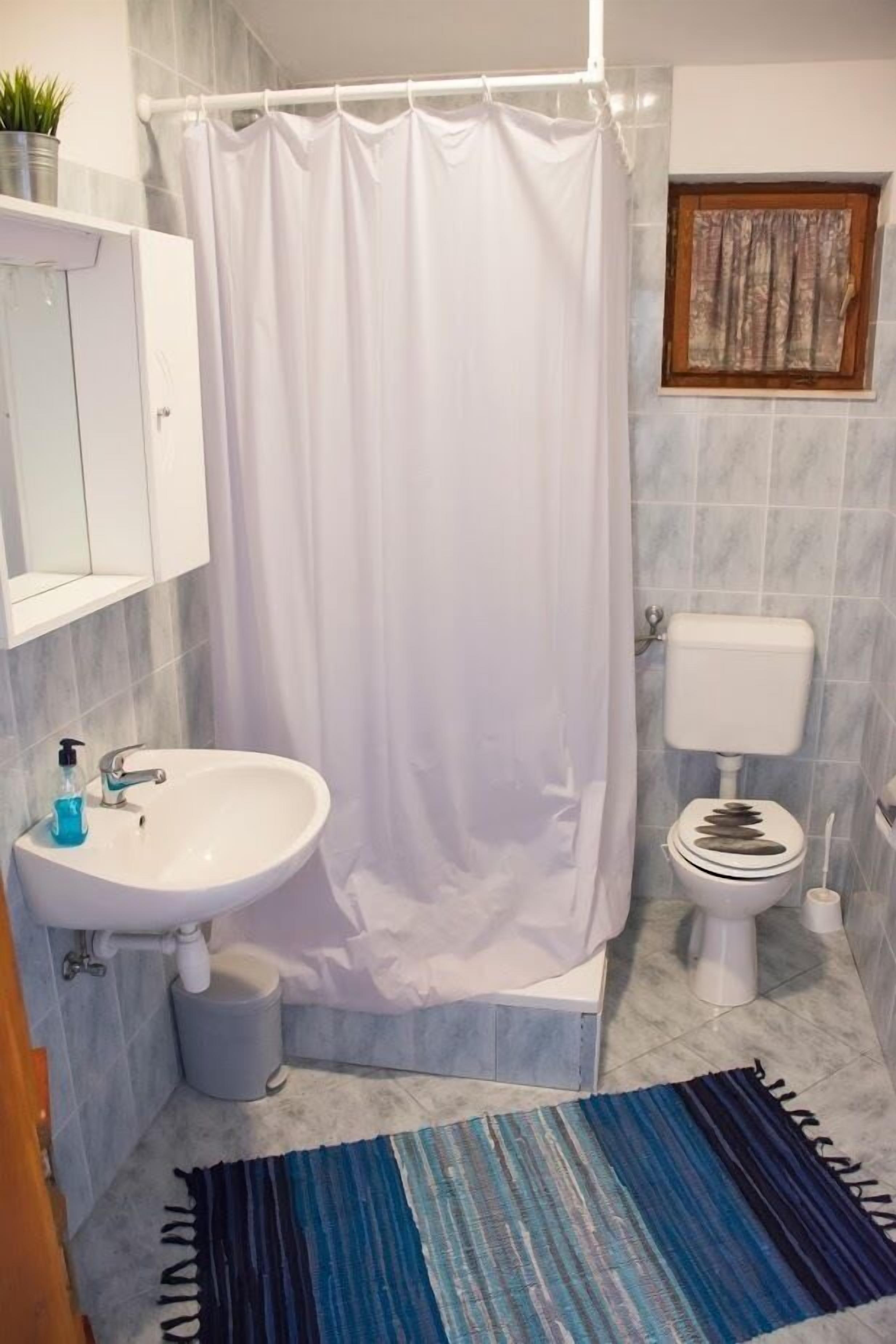 A bathroom with a white sink, toilet, and shower curtain.
