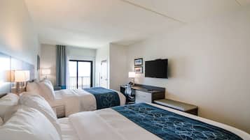 Habitación de hotel con dos camas, un escritorio, televisión y ventana con vistas.