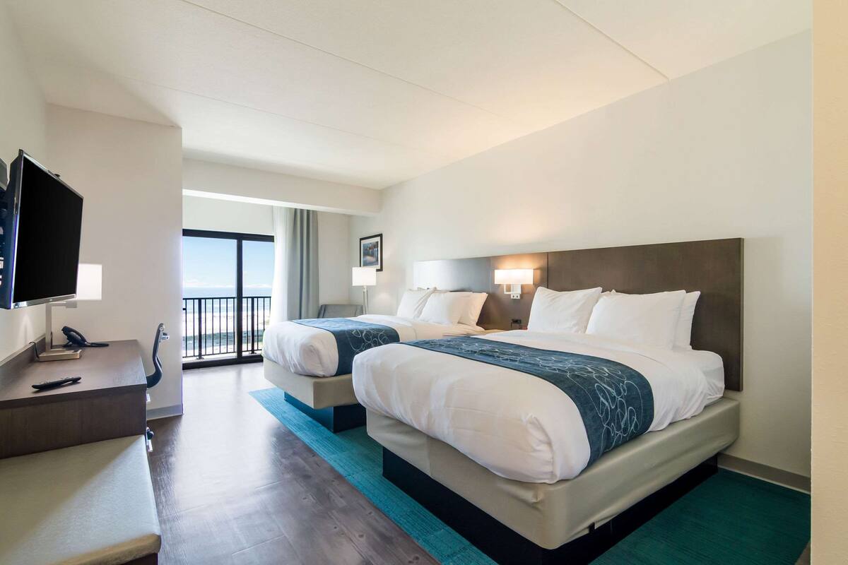 A hotel room with two beds, a desk with a telephone, and a television.