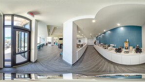 A modern hotel lobby with a curved glass wall, a coffee bar, and a seating area. - Comfort Inn & Suites Gulf Shores East Beach near Gulf State Park (Gulf Shores)