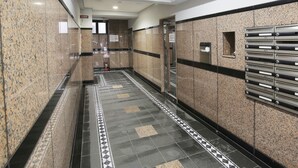 A corridor with granite walls, a tiled floor, and mailboxes on the right. - Grand Court Namba 501 (Osaka)