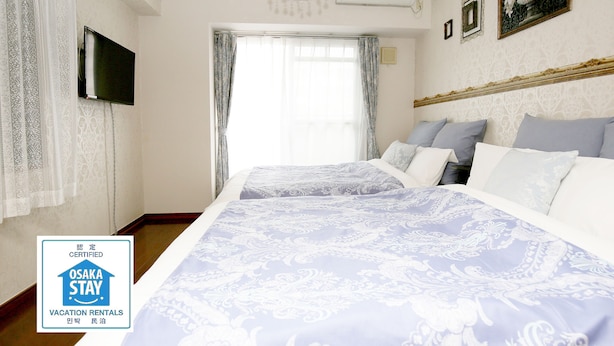 A hotel room with a large bed, a television mounted on the wall, and a chandelier. - Grand Court Namba 501 (Osaka)