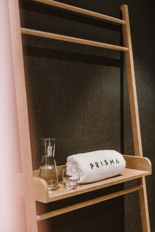A wooden chair with a towel labeled "PRISMA" and a glass bottle on a shelf. - PURO Warszawa Centrum (Warsaw)