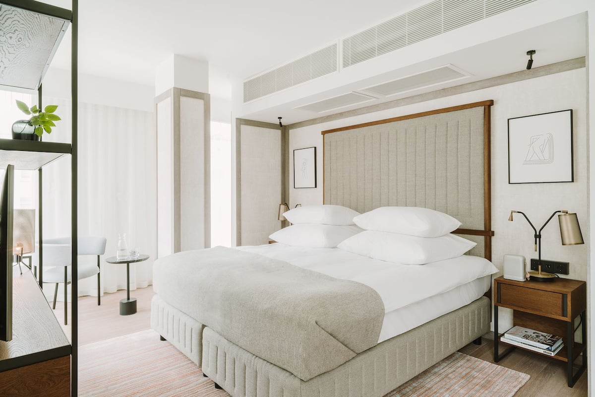 Ein modernes Schlafzimmer mit einem großen Bett, Nachttischen, einem Schreibtisch und einem Stuhl.