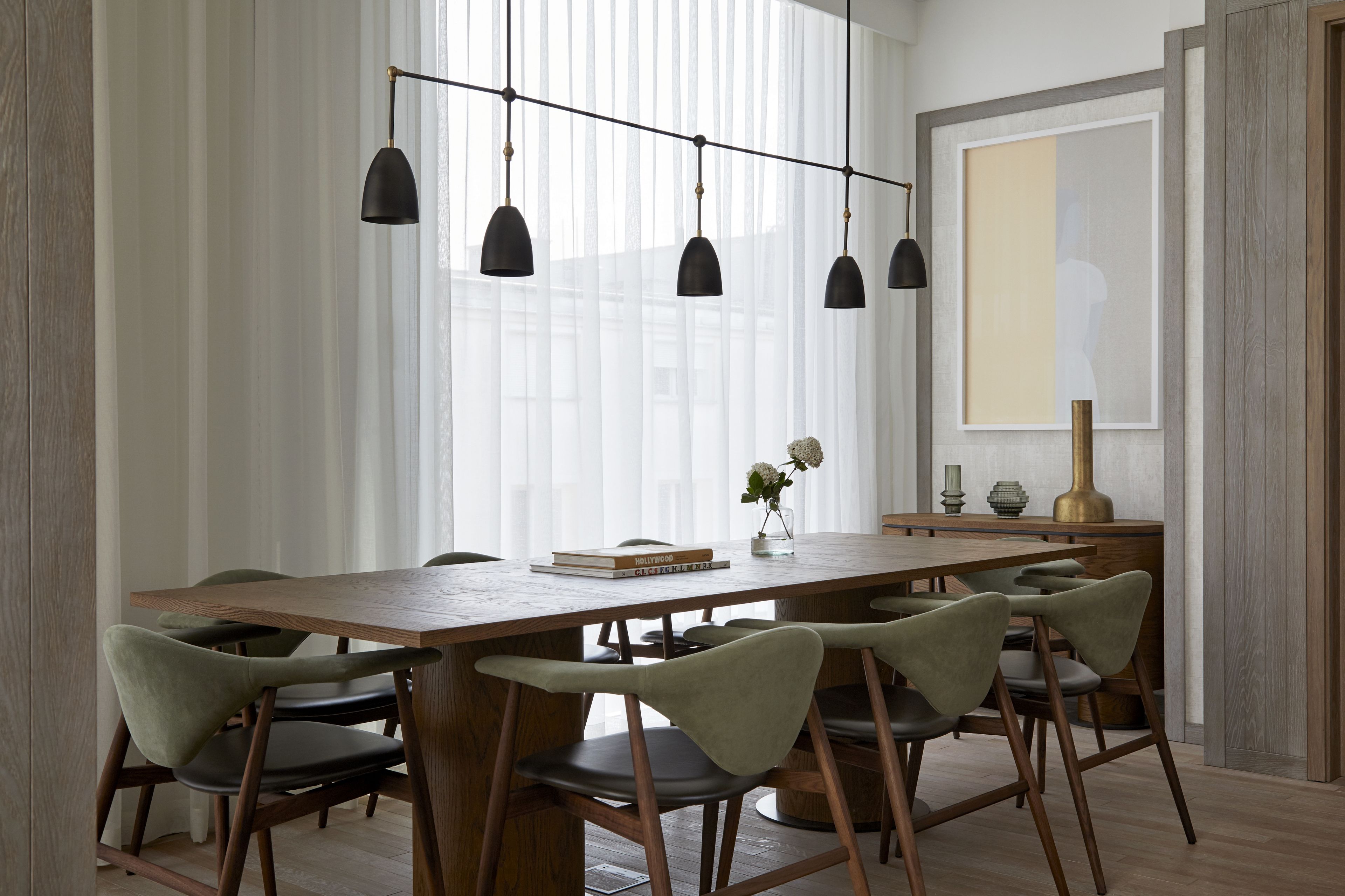 Un comedor con una mesa de madera, seis sillas y lámparas colgantes.