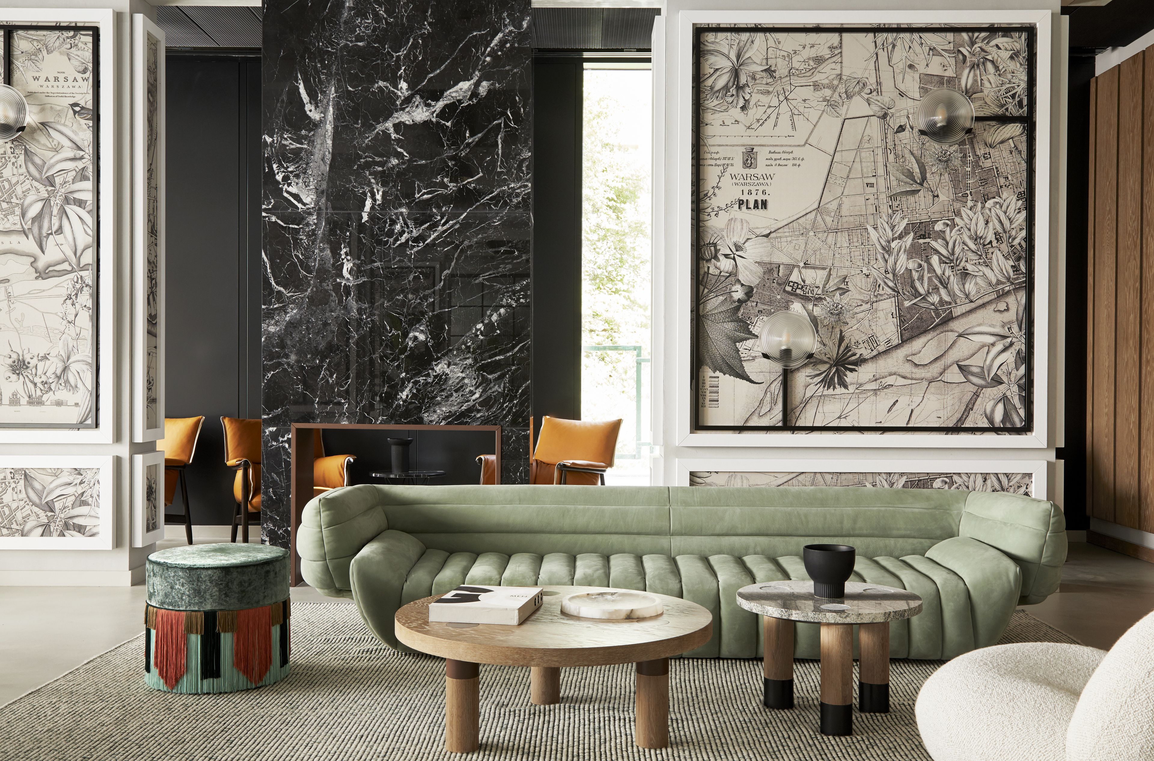 A modern living room with a green sofa, round coffee table, and a large black and white map mural on the wall.