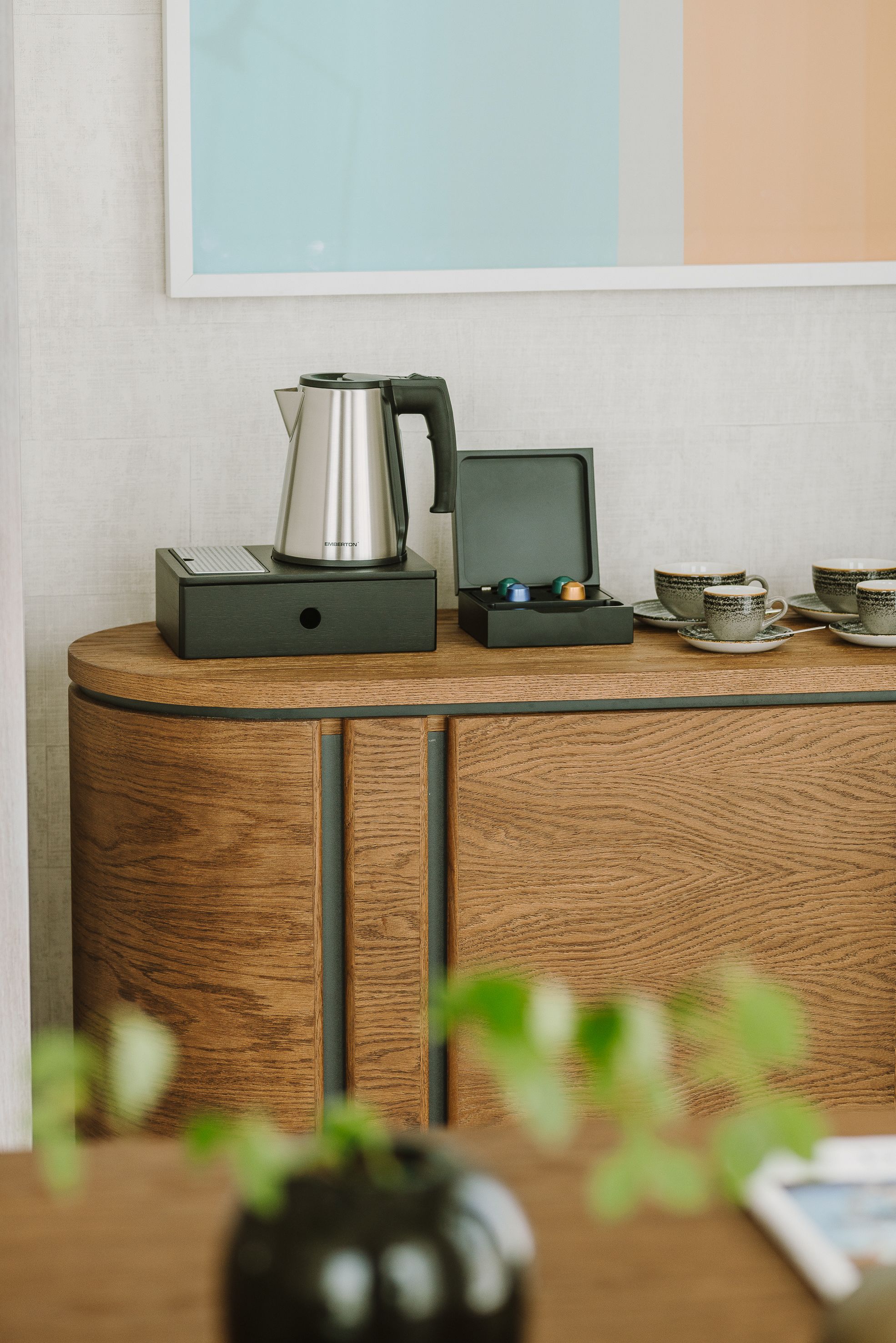A wooden cabinet with a coffee maker and cups on top.