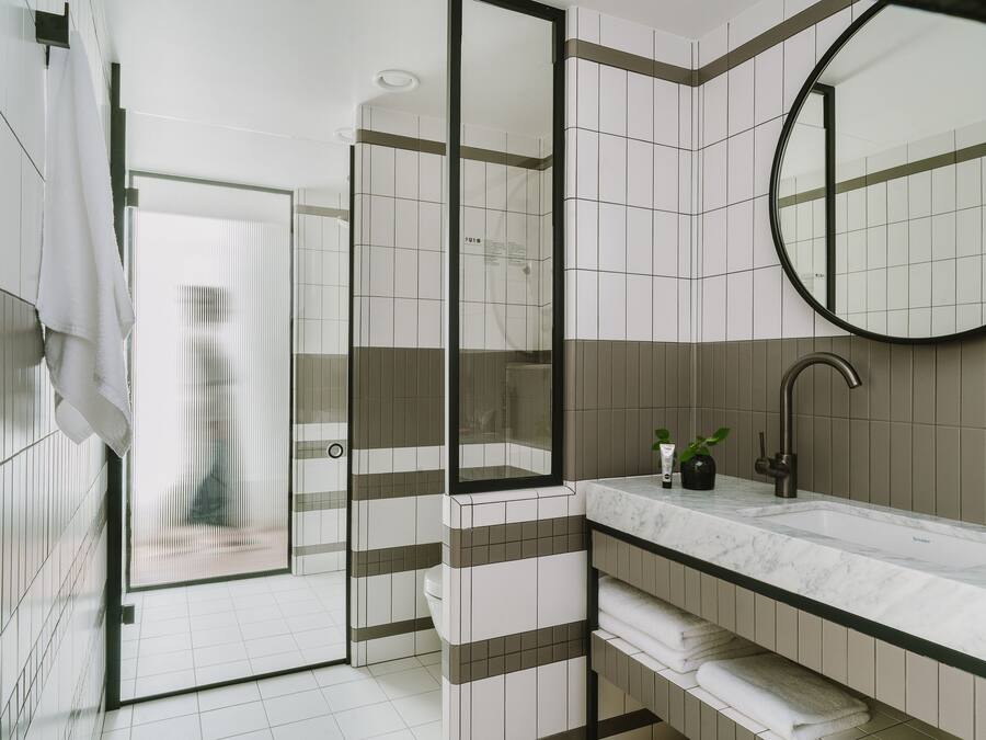 Un baño moderno con cabina de ducha de vidrio, lavamanos de mármol y un espejo grande.