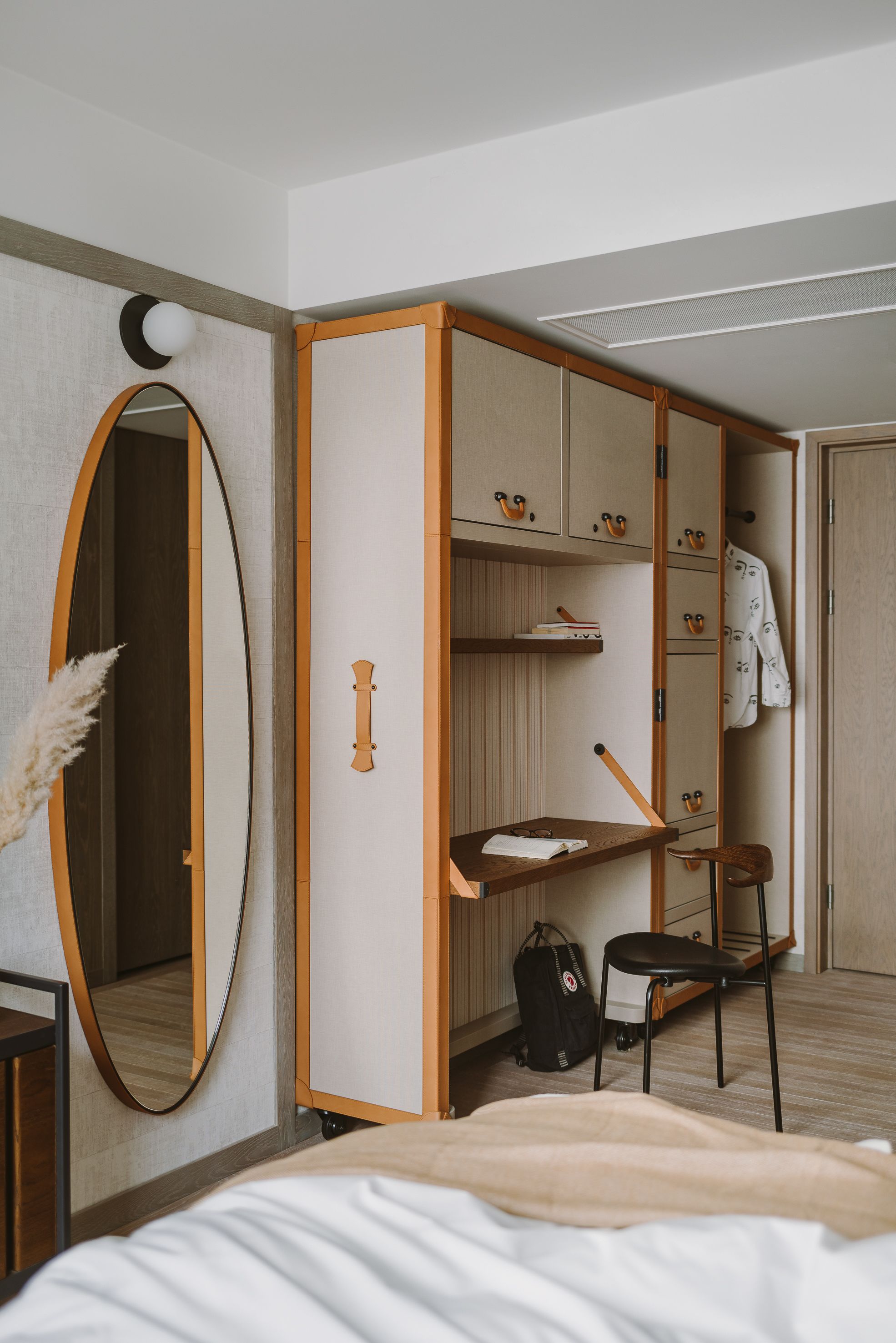A bedroom with a bed, a desk with a chair, a wardrobe, and a mirror.