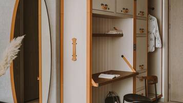 A bedroom with a bed, a desk with a chair, a wardrobe, and a mirror.