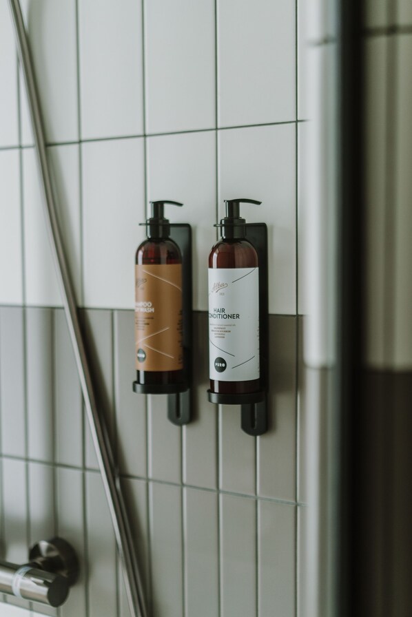 Dos botellas de acondicionador y champú sujetas a una pared de azulejos.