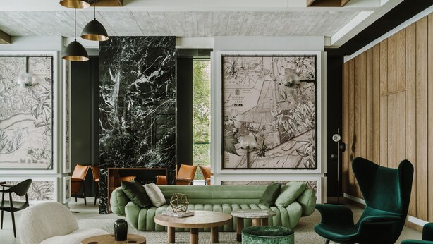 A modern living room with a green sofa, a green armchair, and a round coffee table. There are two pendant lights hanging from the ceiling, and a large black and white map on the wall. - PURO Warszawa Centrum (Warsaw)