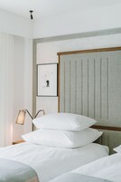 Una cama bien tendida con sábanas blancas y un cabecero con listones verticales.
