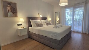 A bedroom with a bed, bedside lamps, a nightstand, a mirror, and a window with curtains. - Apartments Bubalo Hvar (Hvar)